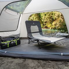 a tent with two chairs and a sleeping bag in front of it on the ground