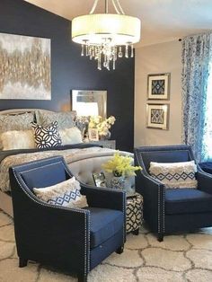 a bedroom decorated in blue and white with chandelier above the bed, two chairs