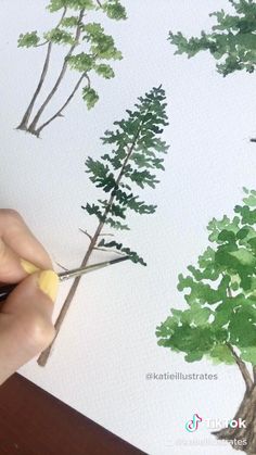 someone is using scissors to paint trees on the paper with watercolors and ink