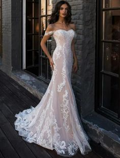 a woman in a white wedding dress standing on a wooden floor next to a building