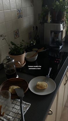 a kitchen counter with plates and utensils on it, next to a potted plant