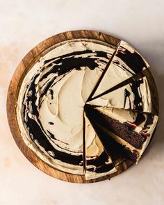 a chocolate cake with white frosting on a wooden platter, cut into slices