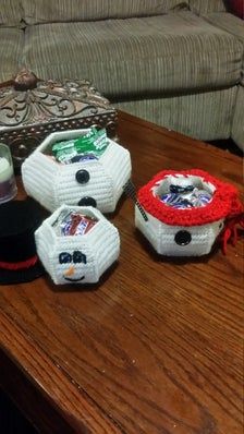 three knitted snowmen sitting on top of a wooden table next to a couch