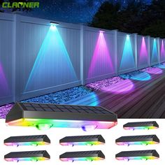 several different colored lights on the side of a white fence next to a wooden deck