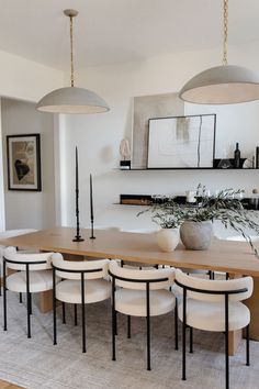 a dining room table and chairs with plants in the vases on each one side