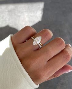 a woman's hand wearing a gold ring with an oval shaped diamond on it