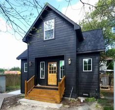 a small black house with wooden steps leading up to the front door