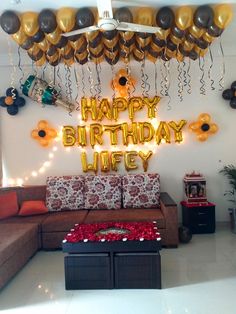 a living room with balloons and decorations on the wall, couches and coffee table