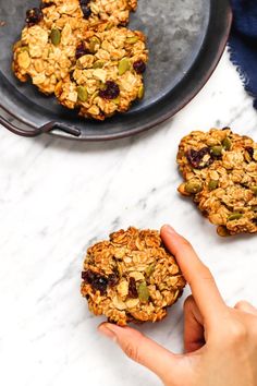 someone is holding their hand out to grab some oatmeal cookies from the plate