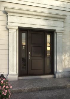 the front door of a white building with flowers on the steps