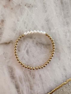 14k gold filled beaded bracelet with fresh water pearls on stretchy string. Please measure your wrist and select your size in the dropdown as this bracelet is not one size fits all. SIZING TIP: To find out your bracelet size, wrap a piece of string around your wrist to measure (place it just above the wrist bone.) Then measure the length of the string. Then I'd recommend adding 0.8 inches (2cm) to that measurement to get your correct bracelet size. Gold Beaded Bracelet, Dope Jewelry