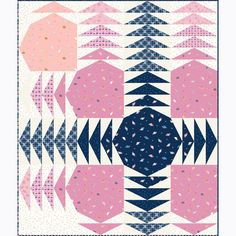 a pink, blue and white quilt with an abstract design on the back ground in front of it