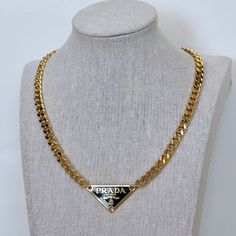 Vintage Prada pendant on a gold curb chain necklace. Repurposed from authentic Prada bag. Luxury Gold Charm Necklaces With Adjustable Chain, Luxury Gold Charm Necklace With Adjustable Chain, Gold Plated Pendant Chain Necklace, Luxury Gold-tone Medallion Chain Necklace, Luxury Gold-tone Brass Chain Necklace, Gold Chain Brass Pendant Necklace, Gold Chain Pendant Necklace In Brass, Luxury Gold Chain Medallion Necklace, Luxury Gold Necklace With Figaro Chain