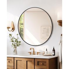 a bathroom vanity with a round mirror above it and a vase on the counter top