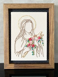 the embroidery art is displayed in a wooden frame