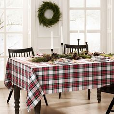 the table is set for christmas dinner with plaid cloth