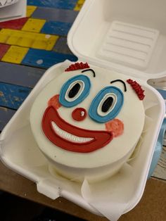 a close up of a cake in a box with a clown face on it's side