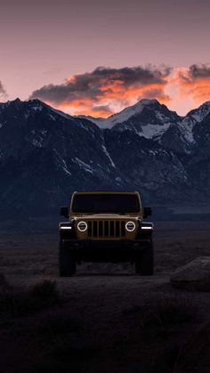 a jeep is parked in the desert with mountains in the background