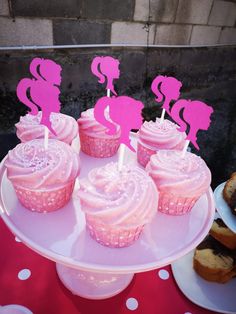 cupcakes with pink frosting and flamingos on top are sitting on a cake plate