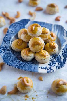 a blue and white plate filled with small pastries next to cashews on a table