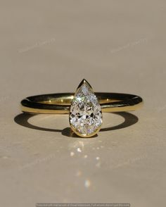 a yellow gold ring with a pear shaped diamond