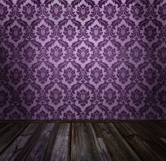 an empty room with purple wallpaper and wood flooring in front of the wall