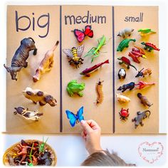 a young boy is playing with toys in front of a poster that says, big and small