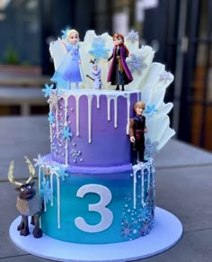 a frozen princess themed birthday cake with figures on the top and number three frosting