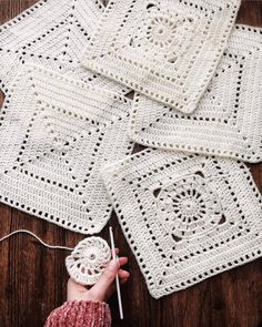 crocheted squares are arranged on top of a wooden table