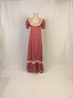 "vintage 1970s full length dress empire waist red/white floral print lace trim puff short sleeve w/elastic ruffled cuff scoop neck empire waist ruffle skirt hem lace around neck looks older, like antique lace perhaps tie back zipper up back 50/50 cotton/polyester good vintage condition, light wear label size 11/12-n/a-see below measures, lying flat, shoulder-14 1/2\" sleeve-10\" chest-17\" waist-15\" length-56 1/2\"" 70s Empire Waist Dress, Fitted Square Neck Maxi Dress With Lace Trim, Victorian Cotton Summer Dress, Victorian Style Cotton Summer Dress, Victorian Style Summer Dresses, Victorian Cotton Dress For Summer, Fitted Vintage Dress With Vintage Print, Summer Vintage Dress With Empire Waist, Fitted Short Sleeve Maxi Dress With Lace Trim