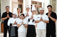 a group of people standing next to each other in front of a building with their hands together