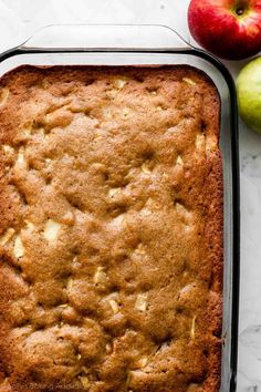 an apple cake in a pan next to two apples