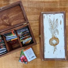 an open wooden box filled with cards and other crafting supplies sitting on top of a wooden table