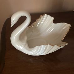 a white swan shaped bowl sitting on top of a wooden table