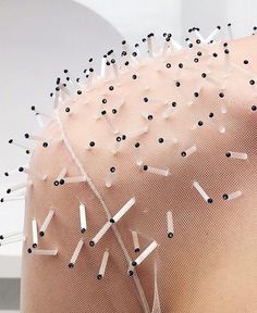 the back of a woman's head with pins stuck in her hair and nails sticking out of it