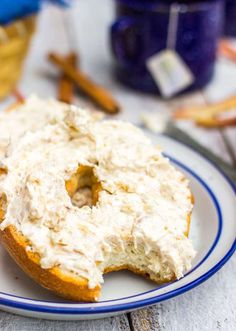 a bagel covered in white frosting sitting on top of a blue and white plate