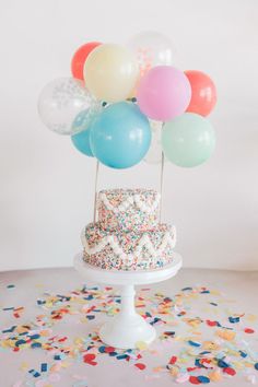 a birthday cake with sprinkles and balloons