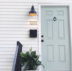 the front door of a house with a potted plant next to it and a light on