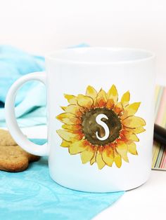 a sunflower with the letter s painted on it next to a cookie and pen