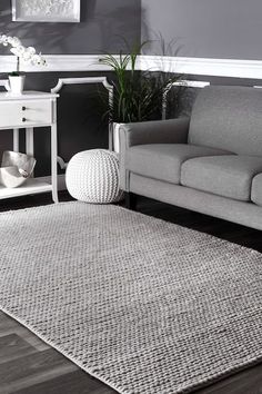 a living room with a gray couch and white rug on the floor in front of a grey wall