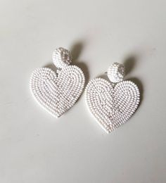 "Handmade white beaded Heart shape embroidered Earring Purely handmade seed beads embroidered heart earring looks so great. An ideal gift for bridesmaids. Earrings measure about approx. 2.10\" long and 2.10\" wide. PS: Carnation jewelry is handmade & handcrafted in India hence there is a possibility of a slight or small imperfection due to the fact that these are made by hand. I still make sure that every piece made here is perfect to look at. For more details, please see our shop policies f White Heart Beads Jewelry For Party, White Beaded Earrings With Heart Beads As A Gift, White Dangle Heart Bead Earrings, White Heart Bead Dangle Earrings, White Heart Beads Dangle Earrings, White Dangle Heart Earrings With Beads, White Heart Charm Earrings For Party, White Double Heart Earrings For Wedding, White Double Heart Wedding Earrings