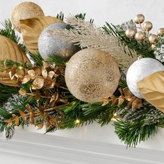 christmas decorations on a mantle with gold and silver ornaments