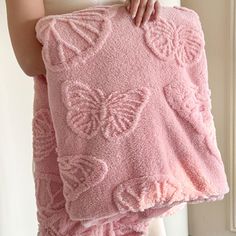 a woman is holding a pink towel with butterflies on it and she has her hands in the pocket