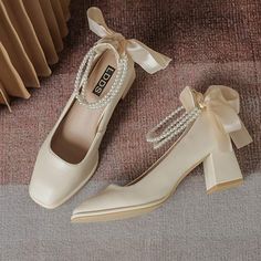 a pair of beige shoes with pearls on the heel and ribbon tied around the toe