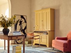 a living room filled with furniture and a large painting on the wall above a desk