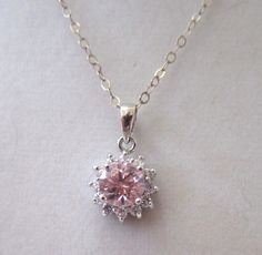 "Don't take your good jewelry with you on vacation when you can still look elegant in CZs! This necklace features a pink Cubic Zirconia solitaire stone surrounded by clear CZ stones. All are set into an 18K setting and hang from a sterling silver chain. The back of the pendant is marked 18K and the chain sterling silver. The length of the pendant is 18\" when worn and the pendant drop itself measures 1/2\" in diameter. Well-made and in excellent condition." Pink And Silver Necklace, Pink Jewelry With Diamond Accents In Cubic Zirconia, Pink Jewelry With Diamond Accents, Elegant Pink Jewelry With Center Stone, Silver And Pink Jewelry, Pink Brilliant Cut Jewelry For Gift, Dazzling Pink Jewelry As A Gift, Pink Cubic Zirconia Jewelry With Diamond Accents, Sterling Silver Jewelry With Pink Center Stone