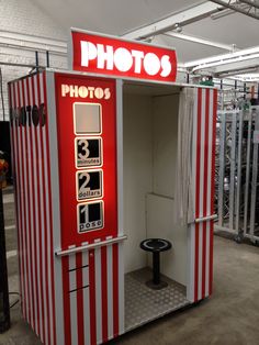 an old fashioned red and white photo booth in a warehouse or shop with the door open