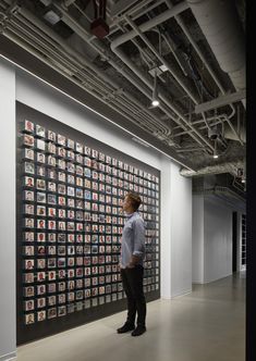 a man standing in front of a large wall with pictures on it's sides