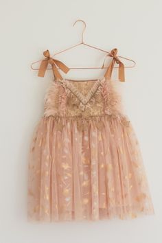 This golden peach tutu dress is the perfect addition to your little ones wardrobe One of a kind design The skirt is crafted from multiple layers of soft peach tulle, creating volume and the top layer features a gold feather design that creates a dreamy effect, perfect for twirling and dancing! The bodice is constructed from sparkly sequin fabric and delicately adorned with ruffled tulle, peach feathers and gold star trim The gold satin ribbon ties ensure a customisable fit, making it easy to adj Cute Summer Fairy Dress With Tulle Skirt, Cute Peach Party Dress, Peach Tulle Dress For Spring, Whimsical Tulle Princess Dress For Summer, Gold Princess Dress For Summer Dress-up, Gold Tulle Dress For Spring, Peach Princess Dress For Summer, Peach Princess Style Summer Dress, Gold Tulle Tutu Dress With Ruffles