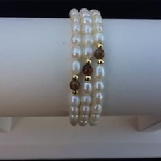 Cultured Freshwater Pearls, Tiger Eye, And Goldtone Beads Memory Wire Bracelets. Since Pearls And Gemstones Are Natural Materials, There Are Natural Differences In Each. Approx. 55mm In Diameter. Approx. 4-5mm Pearls, 2mm Goldtone Beads, And 4mm Gemstones. White Single Strand Beaded Bracelet For Gift, White Round Beaded Single Strand Bracelet, White Pearl Rondelle Necklace With Gemstone Beads, White Pearl Necklace With Rondelle Gemstone Beads, White Pearl Beaded Bracelets With Natural Stones, White Pearl Beaded Bracelets With Polished Beads, Adjustable White Pearl Necklace With Natural Stones, White Polished Pearl Beaded Bracelets, White Pearl Jewelry With Gemstone Beads